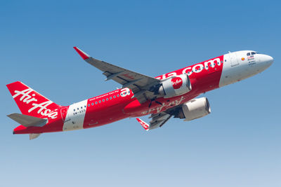 Low angle view of airplane flying against clear blue sky