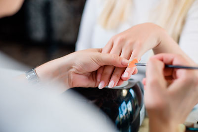 Close-up of stylist painting woman nails at salon