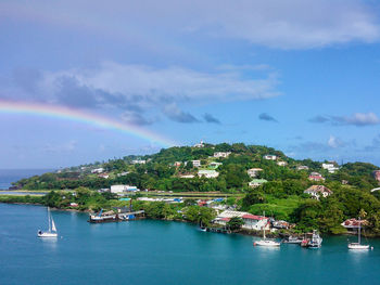 Scenic view of rainbow over sea and buildings