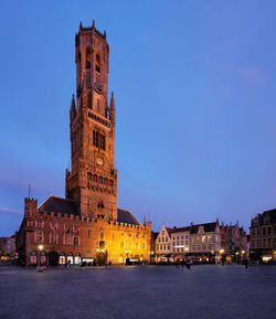 Illuminated buildings in city against sky at dusk