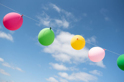 Colorful bright balloons on a string on a blue sky background