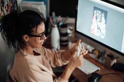 Rear view of woman using mobile phone while sitting on table