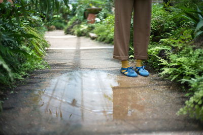 Low section of person standing on wet footpath