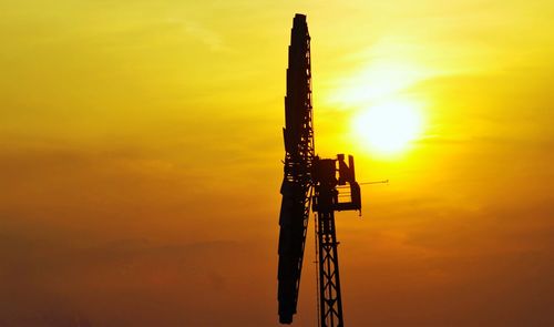 Low angle view of silhouette crane against sky during sunset