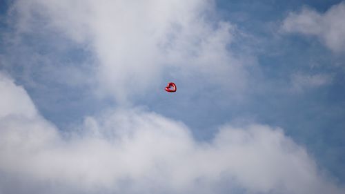 Low angle view of red paragliding against sky