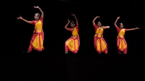 Group of people dancing against black background