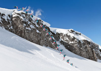 Low angle view of people skiing on snowcapped mountain against sky