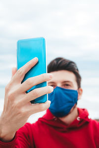 Close-up portrait of woman holding blue water against sky