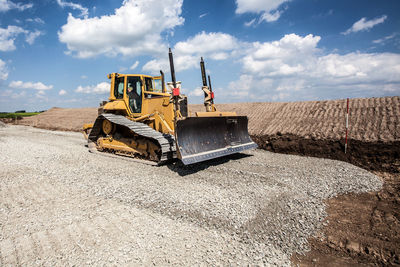 Man driving bulldozer at construction site against sky