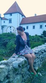 Young woman sitting in front of house