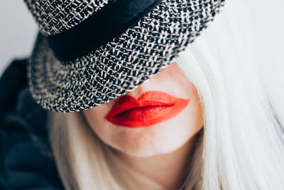 Close-up portrait of woman in red lipstick wearing hat