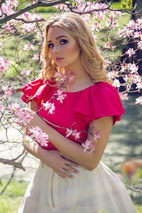 Portrait of a young woman blondes with make-up in the cherry sakura pink white in a white skirt