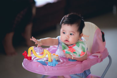 Cute baby girl in walker at home