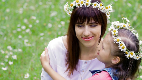 Summer, amidst a chamomile lawn, in the forest, a young woman, a brunette and a girl of seven