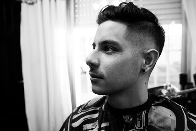 Close-up of young man looking away while siting at barber shop