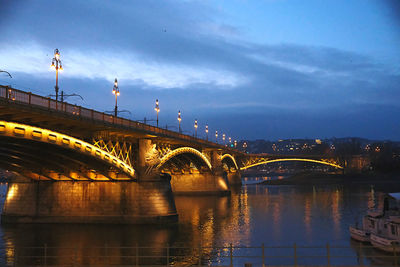 Illuminated bridge over river against sky at night