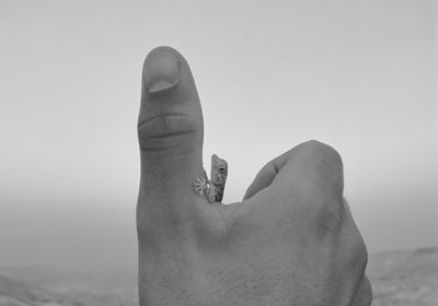 Close-up of hand holding rock against clear sky