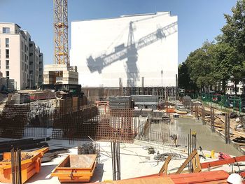 Cranes at construction site in city against sky