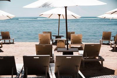 Chairs on beach by sea against sky