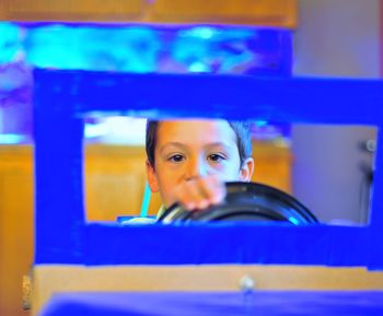 Portrait of boy enjoying blue toy car ride