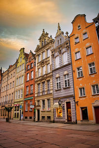 Residential buildings by street against sky during sunset