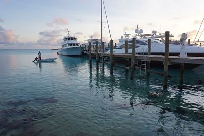 Boats moored at harbor against sky
