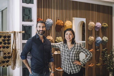 Portrait of smiling male and female sales colleagues standing together at fashion store