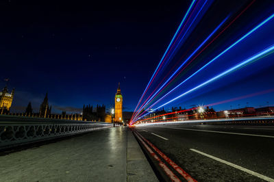 Light trails on bridge with illuminated big ben in background at night