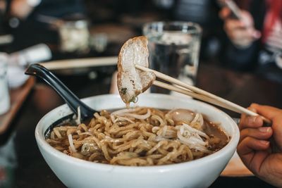 Close-up of person holding noodles in bowl