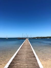 View of pier over sea against clear blue sky