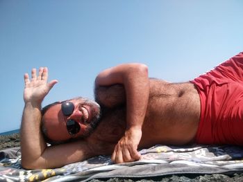 Midsection of man lying down against clear sky