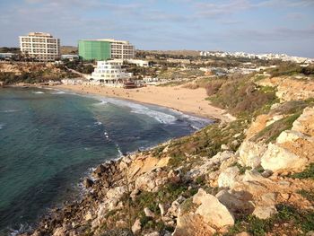 Scenic view of beach by city against sky