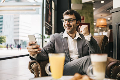 Smiling businessman using mobile phone at restaurant