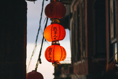 Low angle view of illuminated chinese lanterns hanging amidst buildings