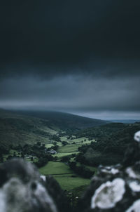 Scenic view of landscape and sea against storm clouds