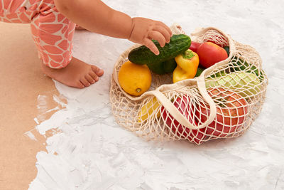 Cropped image of girl picking fruit from bag