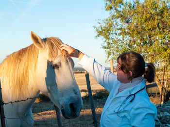 Doctor touching horse on field