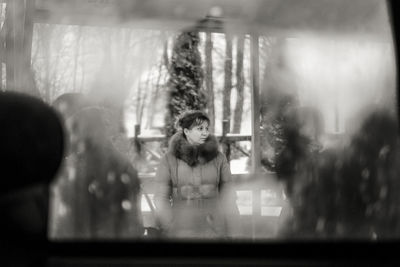Defocused image of young woman standing by window
