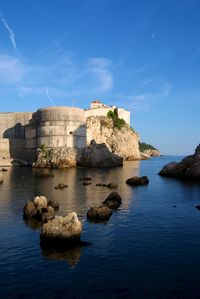 Built structure by sea against blue sky