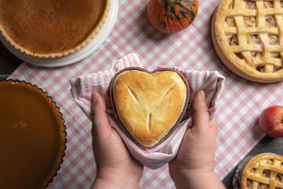 Cropped hand holding heart shape pie