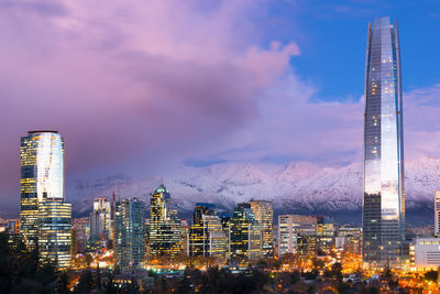 Illuminated buildings against cloudy sky at dusk