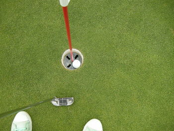 High angle view of canvas shoes and golf club by hole at course