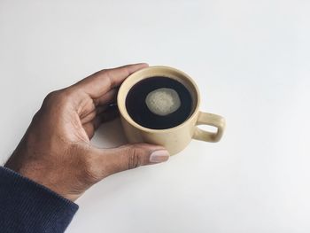 Close-up of hand holding coffee cup against white background