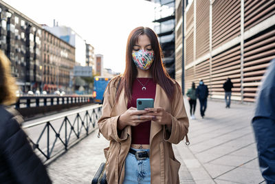 Full length of young woman using phone on street