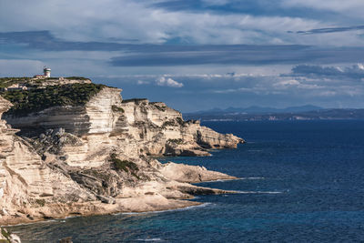 Scenic view of sea by cliff against sky