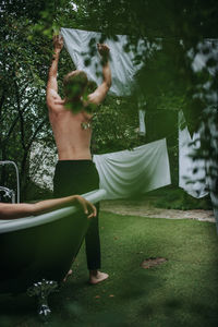 Rear view of shirtless woman standing in water