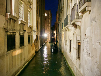 Wet street amidst buildings in city at night