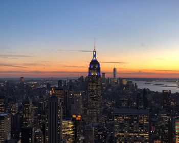 Illuminated cityscape against sky during sunset