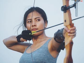 Close-up of woman aiming bow outdoors