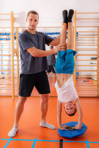 Balance exercises for children, child doing a hand stand with trainer